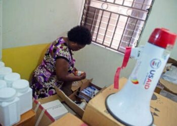 Una enfermera busca en cajas como un megáfono con un "USAID" El logotipo en él se ve en primer plano