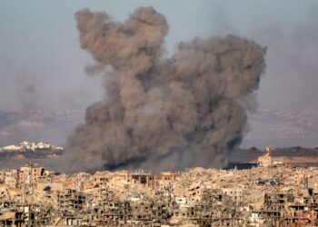 Plumas de humo que se elevan de una ciudad bombardeada.