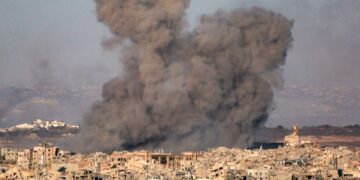Plumas de humo que se elevan de una ciudad bombardeada.