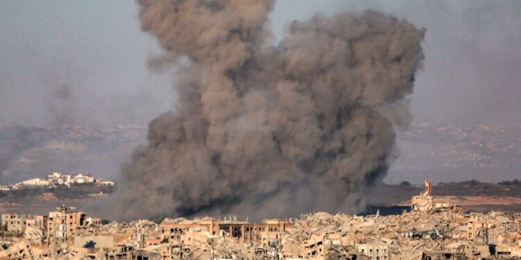 Plumas de humo que se elevan de una ciudad bombardeada.