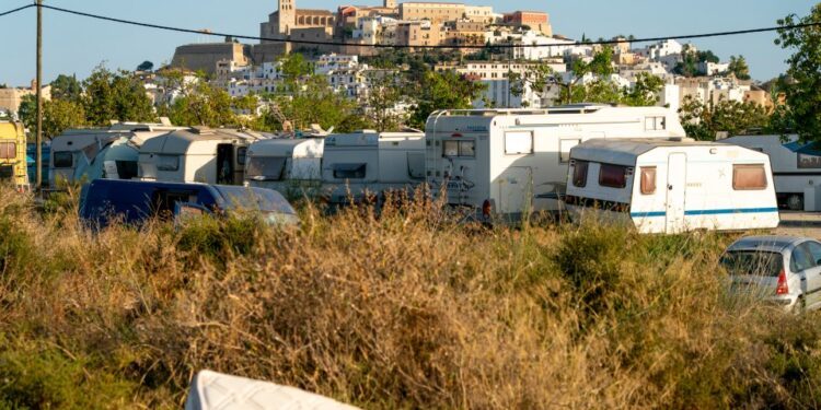 RVS estacionados en un campo con una ciudad en el fondo.