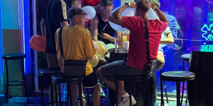 Personas que inhalan óxido nitroso de globos en una barra.