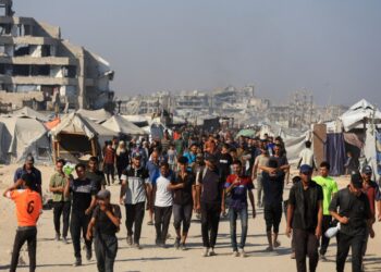 Los palestinos que caminan cerca de edificios y carpas dañados en Gaza, esperando ayuda.