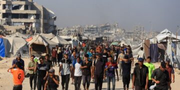 Los palestinos que caminan cerca de edificios y carpas dañados en Gaza, esperando ayuda.