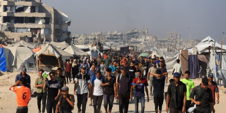 Los palestinos que caminan cerca de edificios y carpas dañados en Gaza, esperando ayuda.