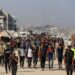 Los palestinos que caminan cerca de edificios y carpas dañados en Gaza, esperando ayuda.