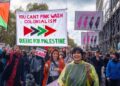 Los manifestantes marchan bajo una lectura de banner "No puedes el colonialismo de color rosa; Queers para Palestina" Durante una demostración al aire libre