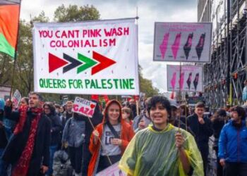 Los manifestantes marchan bajo una lectura de banner "No puedes el colonialismo de color rosa; Queers para Palestina" Durante una demostración al aire libre