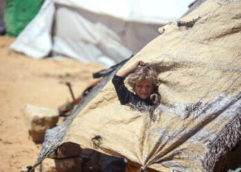 Una niña se levanta a través de un agujero en la tienda en la que vive ella y su familia