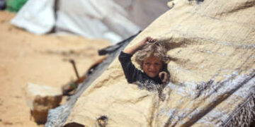 Una niña se levanta a través de un agujero en la tienda en la que vive ella y su familia
