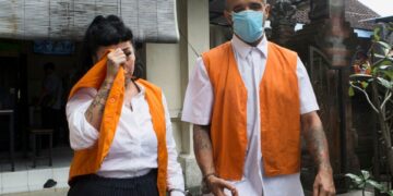 Una mula de drogas británicas y una mujer en chalecos de prisión de naranja se sientan esposados en la corte.