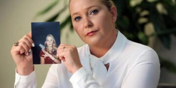 Mujer sosteniendo una foto de una mujer joven con un pájaro.