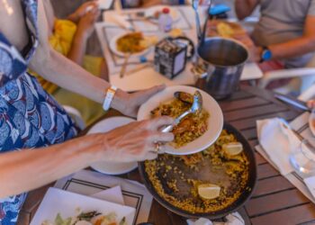 Una persona se sirve paella en un restaurante al aire libre.