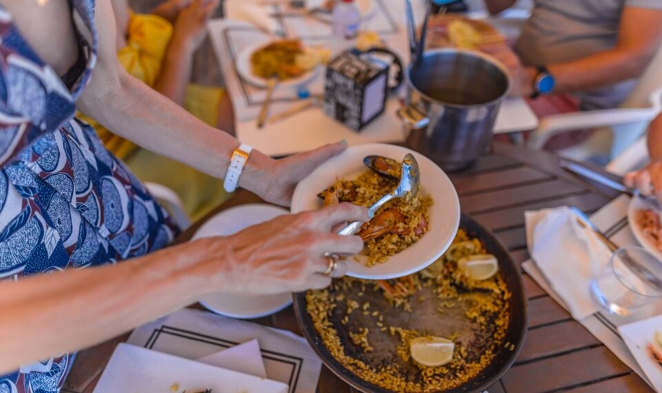 Una persona se sirve paella en un restaurante al aire libre.