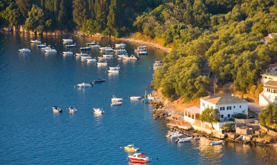 Vista aérea de botes en una bahía cerca de una casa blanca y exuberante vegetación.