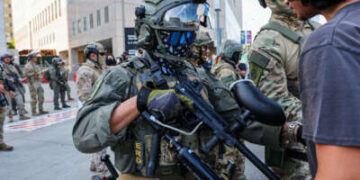 Un ser humano confronta a un agente uniformado y armado de los Estados Unidos