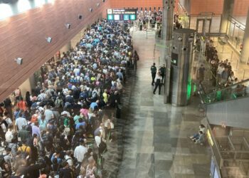 Una gran multitud de personas que esperan en la fila en un aeropuerto.