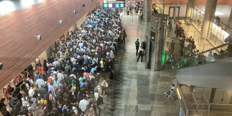 Una gran multitud de personas que esperan en la fila en un aeropuerto.