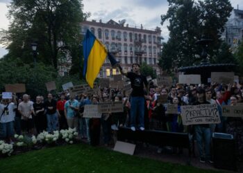 Los manifestantes en Kiev poseen señales y una bandera ucraniana durante una demostración contra una ley que reduce los poderes de las agencias anticorrupción.