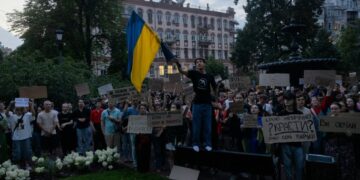 Los manifestantes en Kiev poseen señales y una bandera ucraniana durante una demostración contra una ley que reduce los poderes de las agencias anticorrupción.