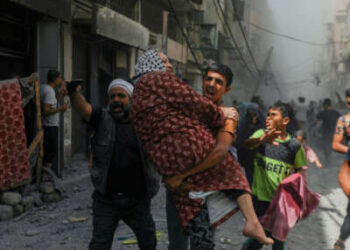 Un niño lleva a una mujer mientras la gente corre por un callejón inmediatamente después de un bombardeo israelí en la ciudad de Gaza, Palestina, el 30 de mayo de 2025.