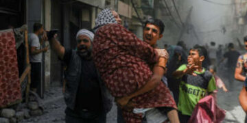 Un niño lleva a una mujer mientras la gente corre por un callejón inmediatamente después de un bombardeo israelí en la ciudad de Gaza, Palestina, el 30 de mayo de 2025.