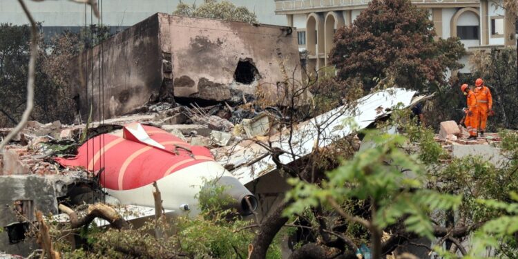 Escombros de un lugar de accidente aéreo con trabajadores de rescate.