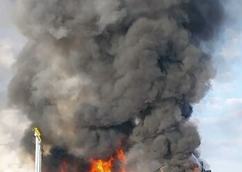 Gran incendio y humo que ondula desde un vehículo en llamas.