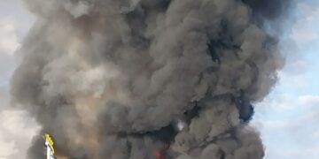 Gran incendio y humo que ondula desde un vehículo en llamas.