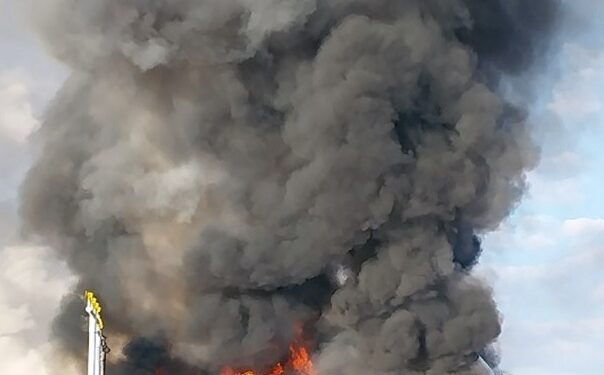 Gran incendio y humo que ondula desde un vehículo en llamas.