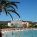 Playa llena de gente en Magaluf, Mallorca, con hoteles en el fondo.