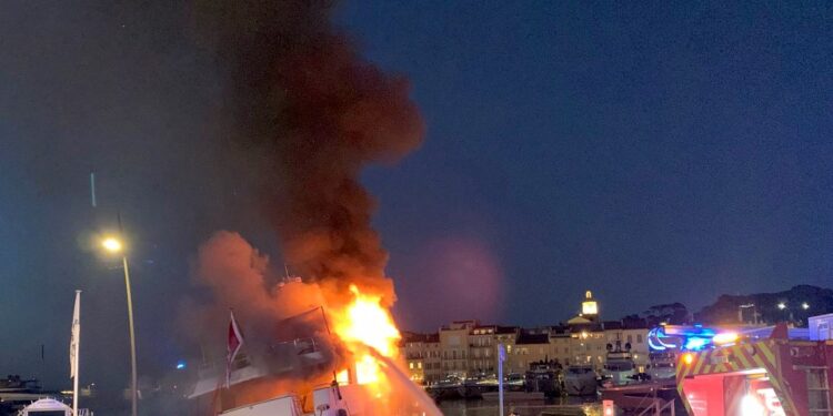 Un superyate envuelto en llamas en el puerto de Saint-Tropez, con bomberos que luchan contra el incendio.