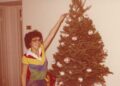 Mujer joven decorando un árbol de Navidad.