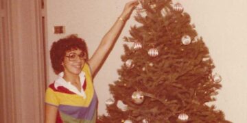Mujer joven decorando un árbol de Navidad.