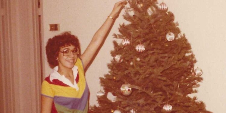 Mujer joven decorando un árbol de Navidad.