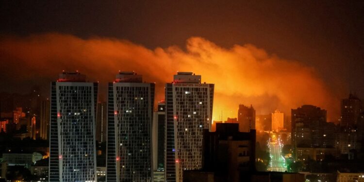 Vista nocturna de un horizonte de la ciudad iluminado por una explosión.
