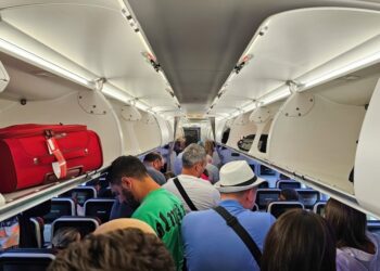 Pasajeros de pie en un pasillo de avión.