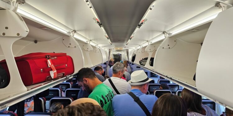 Pasajeros de pie en un pasillo de avión.