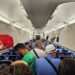 Pasajeros de pie en un pasillo de avión.