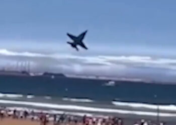 Avión a reacción volando sobre una playa llena de gente.