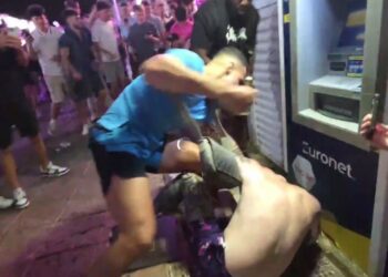 Un hombre con una camisa azul claro golpea a otro hombre durante una pelea en Magaluf.