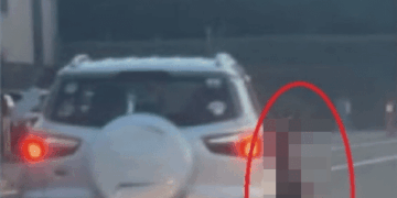 Una imagen borrosa de una persona parada cerca de la parte trasera de un automóvil.