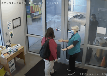 Dos personas con caras se saludan en una puerta.