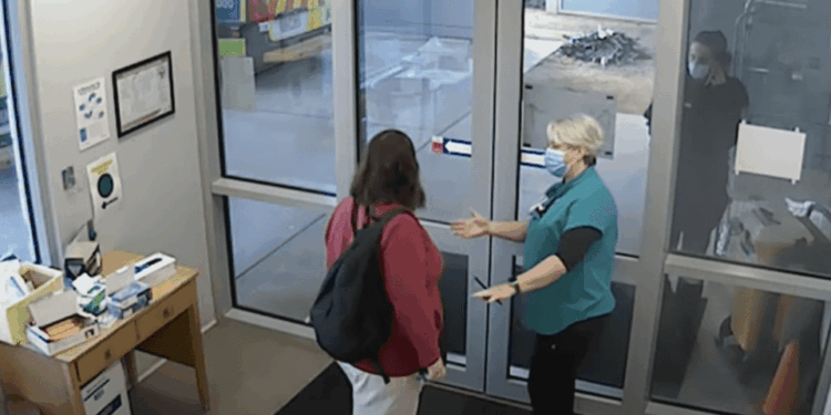 Dos personas con caras se saludan en una puerta.