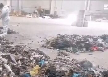 Un trabajador con un traje protector limpia una pila de basura donde se encontró los restos de un bebé.