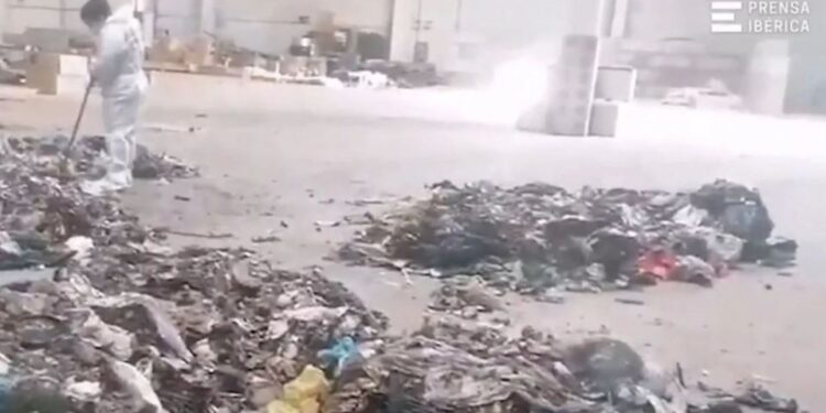 Un trabajador con un traje protector limpia una pila de basura donde se encontró los restos de un bebé.