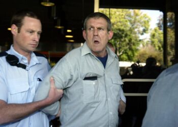 Un oficial de policía lleva a un sospechoso lejos de la Corte Suprema de Adelaide.