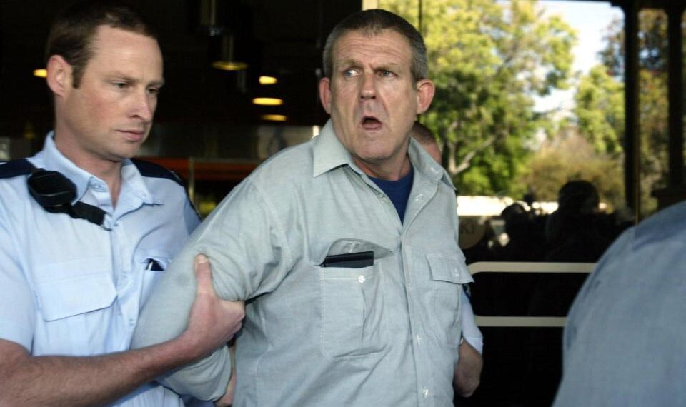 Un oficial de policía lleva a un sospechoso lejos de la Corte Suprema de Adelaide.