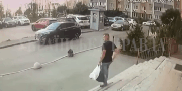 El hombre que lleva una bolsa sube escalones hacia un edificio con autos estacionados en el fondo.