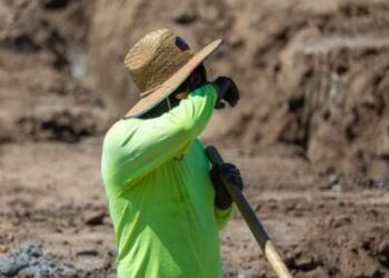 Un trabajador de la construcción se toma un descanso rápido para limpiarse la frente mientras cava una zanja con una pala en medio de una ola de calor en Irvine, California, el 5 de septiembre de 2024.